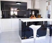 Black with white modern high-tech kitchen with bar chairs and tiled floor