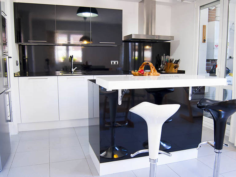 Black with white modern high-tech kitchen with bar chairs and tiled floor
