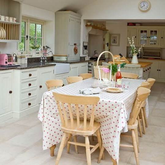 Chairs made of natural wood, table with tablecloth and white wardrobes for kitchen in country style